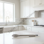 A pair of stainless steel kitchen tongs resting on a white marble countertop in a bright, modern kitchen. A diagonal watermark reading 'Dallas General Wholesale' is overlaid across the center.