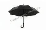 Four umbrellas of different colors standing upright on a white background, with a black umbrella open on a concrete surface.