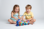 Two children sitting on the floor playing with a colorful, glowing toy train set against a plain light gray studio background. A watermark reading 'Dallas General wholesale' is overlaid across the center.