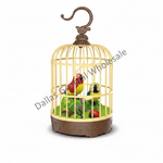 A decorative birdcage figurine with a brown hook handle, cream-colored metal cage bars, and a brown base, containing two small toy birds on a green interior floor. A diagonal 'Dallas General Wholesale' watermark is visible across the product.