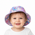 A smiling toddler wearing a wide-brimmed sun hat with a colorful unicorn and rainbow print, photographed against a clean white background.