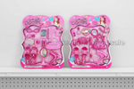 Two pink Barbie-themed toy sets in retail blister packaging, displayed side by side on a white shelf against a white wall. The left set is labeled 'My Beauty Makeup Set' and the right set is labeled 'My Hair Style Set'.