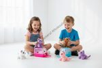 Two children sitting on the floor playing with small plush animal toys and plastic pet carriers in a bright white room. A diagonal 'General Wholesale' watermark is visible across the center.