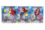Three Barbie-style mermaid dolls in retail packaging, shown side by side on a plain white background. The dolls have long red hair and different colorful mermaid tails, with underwater-themed packaging and a visible 'Dell's General Wholesale' watermark across the center.
