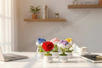 Colorful artificial flowers on a desk with a laptop and notebook in a bright room.