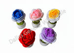 Five crocheted flowers in different colors on a brown surface