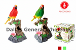 Two colorful parrot bird ornaments perched on tree stump bases are shown on a white background, alongside a product box and a red recording icon. The left parrot is red, yellow, and blue, and the right parrot is green, yellow, and blue.