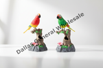 Two small parrot aquarium decorations perched on faux tree stumps, shown on a white studio background with a diagonal Dallas General Wholesale watermark.