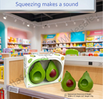 Two green avocado-shaped squishy toys with red pits displayed next to their white and green packaging box on a wooden shelf inside a toy store. A text overlay at the top reads 'Squeezing makes a sound'.