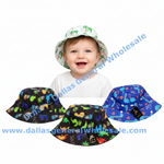 A smiling baby wearing a white bucket hat with a green dinosaur print, with three more bucket hats shown below on a white background. The hats feature colorful dinosaur and plant patterns in blue, black, and white.