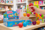 Needz Squeezz Coconut Oil Ball Slushie Squishy toy set, featuring a blue 12-pack box, a small individual box, four colorful squishy balls (purple, blue, orange, red), and a hand squeezing a red ball. Text overlays specify 12 boxes, 10 boxes, and 120 pieces.