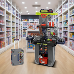 A toy workshop playset with a gray rolling tool cart and a matching gray suitcase, shown in a toy store aisle. The playset includes a workbench, tools, a ladder, and accessories, with the cart labeled 'cool tools' and 'TSA KUMA'.