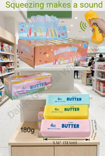 A retail display and stack of Butter Squeishy bars in pastel blue, yellow, and pink, with a hand holding a yellow spray can near the top display. Text overlays read 'Squeezing makes a sound' and show dimensions and weight.