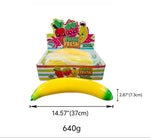 A display box filled with yellow banana-shaped items, shown with a single yellow-and-green banana piece in front. The packaging has fruit illustrations and the text 'VEGA FRESH'.