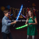 A boy in a blue shirt and a girl in a green dress play with glowing light-up toy swords at a nighttime party. Balloons, string lights, and confetti are visible in the background, and a large watermark reading 'Dallas General Wholesale' is overlaid across the center.