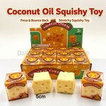 Coconut oil squishy toy set featuring a large display box and two individual packs of cheese-shaped squishies, with three loose yellow cheese-like blocks in front labeled 5cm. The packaging and display prominently read 'SQUEEZE CHEESE' and 'TRY ME!'.