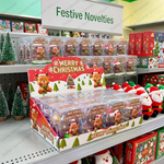 A retail display box filled with Christmas-themed blind bags featuring cartoon reindeer and Santa Claus, shown on a store shelf alongside other holiday toys and decorations.