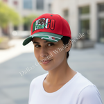 A person wearing a red baseball cap with a green brim and a Mexican flag graphic on the front, photographed outdoors with a blurred background. A diagonal 'Dallas General Wholesales' watermark is visible across the image.