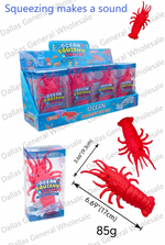 Red plastic squishy lobster toy shown with its blue retail packaging and product details on a white background, including dimensions and text noting it squeaks and comes in a 12-box pack.