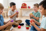 Four young children sitting on a wooden floor in a bright room, smiling and laughing while holding colorful round toy eggs. A red display box of similar eggs sits on a small table in the background.