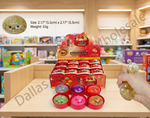 A retail display box and several small round sensory toys are shown on a wooden shelf in a toy store, with a hand squeezing a glitter-filled squishy ball. An inset circle shows a close-up of one toy with text listing size, weight, and dimensions.