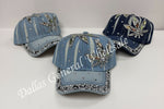 Three blue baseball caps with decorative elements on a white background, branded 'Dallas General Wholesale'.