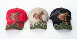 Three baseball caps with embroidered designs on a concrete floor.