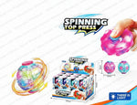 A toy set of colorful spinning tops and a matching retail box on a white background with promotional text. A human hand is shown pressing a pink top, and the image includes dimensions, weight, and quantity details.