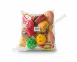 A clear plastic bag containing a set of colorful fruit-shaped squishy toys, photographed on a gray concrete floor. The set includes yellow, orange, red, green, and brown pieces with a white barcode label in the center.