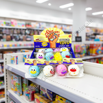 A retail display of Sticker Toys squeeze toys on a store shelf, featuring colorful squishy eggs with cartoon faces. The display includes a yellow and blue header card and several individual toy packages on a white shelf with a blurred store background.