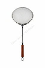 Metal strainer with wooden handle on a cracked concrete floor