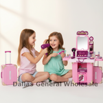 Two young girls playing with a pink toy vanity set and hair dryer on a white floor. The toy set includes a mirror, shelves, makeup items, and a matching pink suitcase.