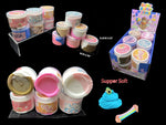 A product display of 144pcs 'Supper Soft' slime containers in various flavors, shown on clear acrylic stands and in a retail display box against a black background. The containers feature colorful labels and lids in pink, blue, white, and brown.