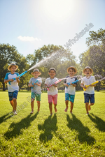 Five children running in a sunny park spraying water from toy sprinklers, with trees and blue sky in the background. A translucent diagonal watermark reading 'Dallas General Wholesale' is visible across the photo.